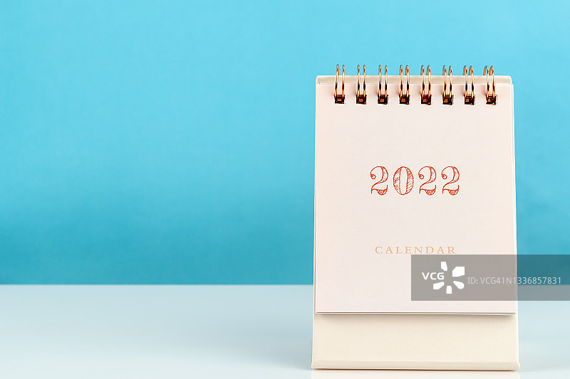 2022年日历桌，供主办方规划和提醒，木制桌面，蓝色背景。图片素材