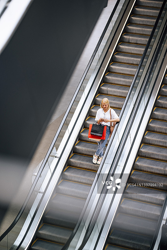美女站在自动扶梯上用手机图片素材