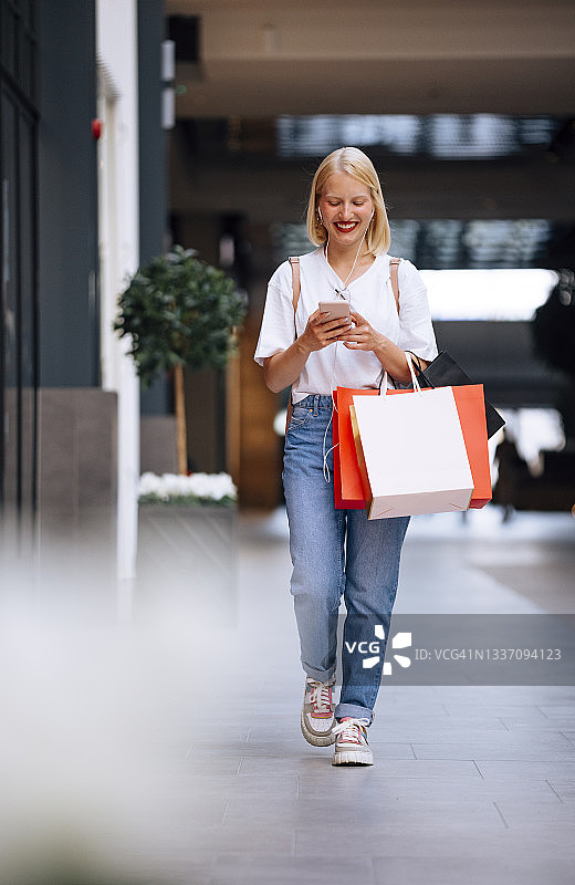 微笑的女人在购物中心使用手机图片素材