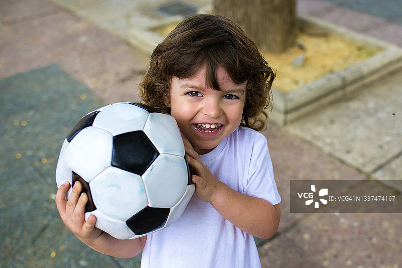 一个手里拿着足球微笑的孩子图片素材