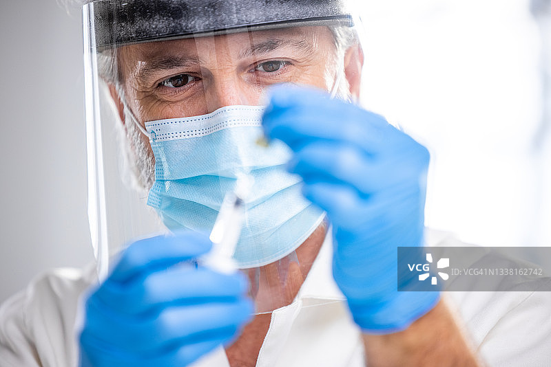 50多岁男性医生正在准备新冠疫苗注射器图片素材