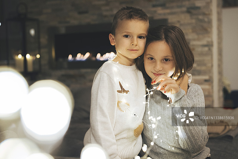 可爱的小孩子，弟弟妹妹裹在闪烁的灯光里图片素材