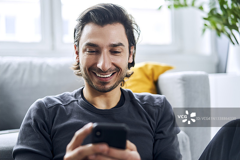 在家用智能手机的快乐男人图片素材