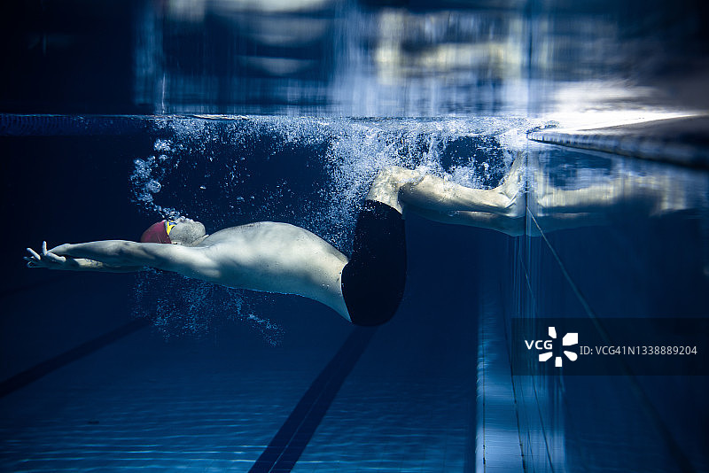 一名男性游泳运动员在室内游泳池练习和训练。水下观察游泳运动的细节。健康的生活方式，动力，能量，运动理念。图片素材