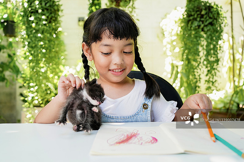 亚洲小女孩写作和花时间和她的猫图片素材