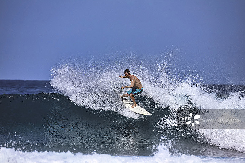 在阳光明媚的日子里，冲浪者在蓝色的波浪上冲浪图片素材