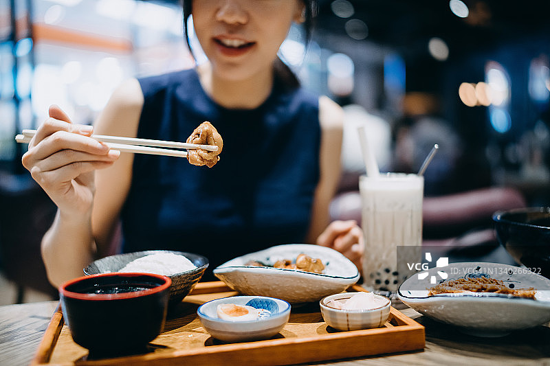 靠近镜头，年轻的亚洲女人享受精致的台湾菜与什锦开胃盘，汤和冰珍珠奶茶在餐厅的餐桌上新鲜。亚洲美食和食物。外出就餐的生活方式图片素材
