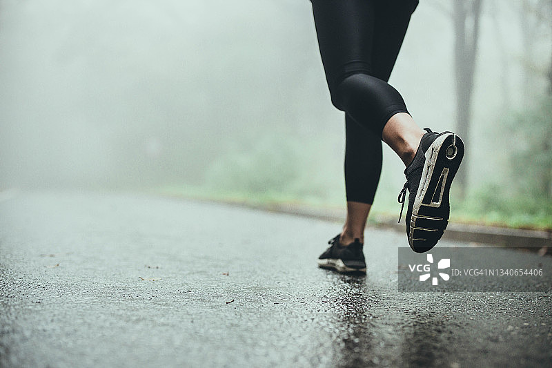 下雨天在路上慢跑的不知名的运动员。图片素材
