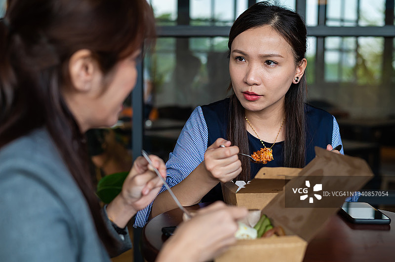 两个亚洲女同事在办公室休息室一起吃饭图片素材
