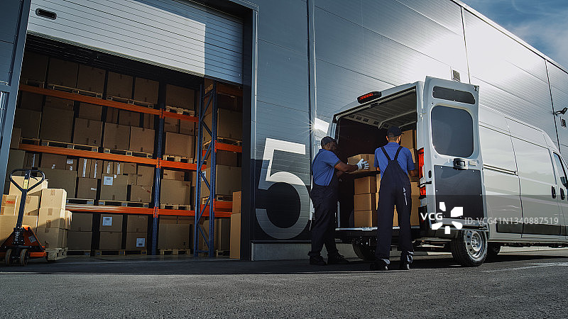 物流配送仓库外:两名工人装载纸箱运送卡车。在线订单，采购，电子商务货物。图片素材