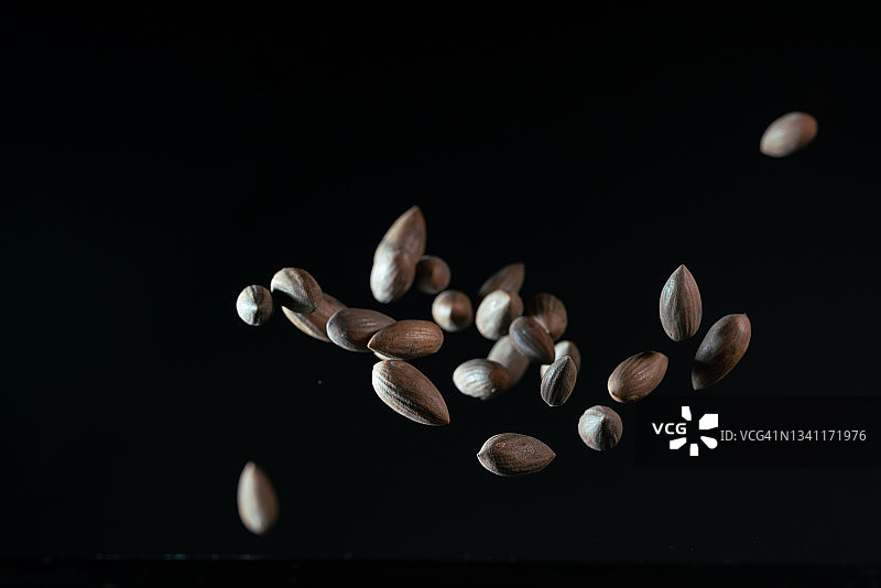 黑色背景下，烤香榧种子在空中飞舞图片素材