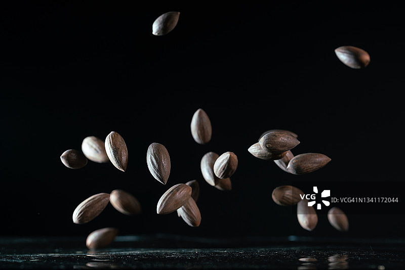 黑色背景下，烤香榧种子在空中飞舞图片素材