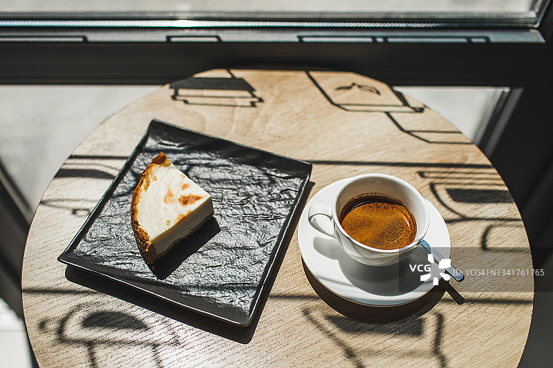 在美丽的自然阳光下，一杯意式浓缩咖啡和新鲜的芝士蛋糕放在桌上图片素材