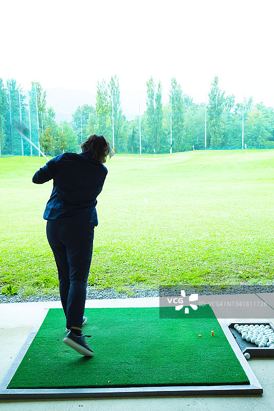 高尔夫球手在一个晴朗的日子里在练习场训练她的高尔夫俱乐部司机图片素材