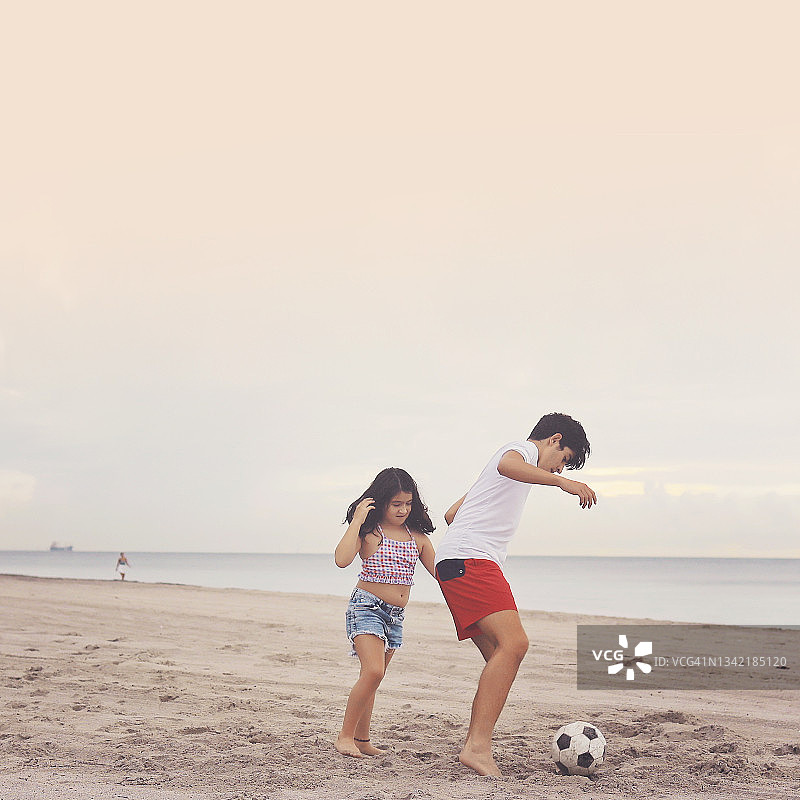 兄弟姐妹在迈阿密海滩踢足球图片素材