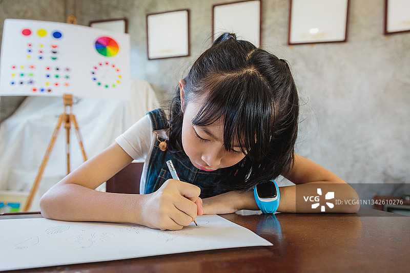 亚洲小女孩在小学用铅笔在纸上画画图片素材
