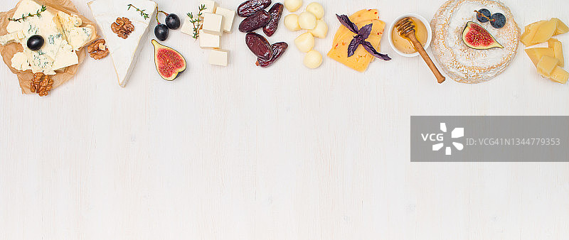 各种类型的奶酪，葡萄，枣，坚果，无花果和蜂蜜在白色的背景与复制空间。旗帜与奶酪板集选择。图片素材