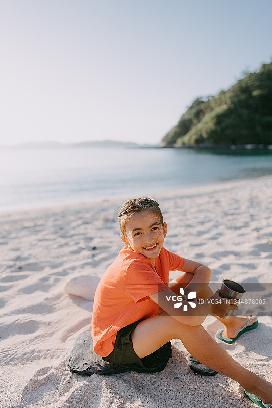 可爱的年轻女孩在日落海滩上对着相机微笑图片素材