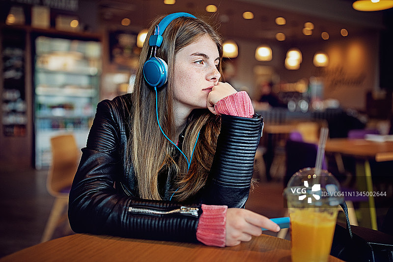 十几岁的女孩在咖啡馆听音乐的肖像图片素材