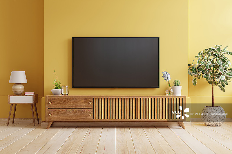 黄色的墙壁背景，电视机安装在一个现代客厅的木柜上。图片素材