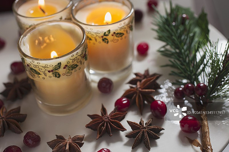 三支装在玻璃杯里的蜡烛，在圣诞节用越桔和八角装饰图片素材