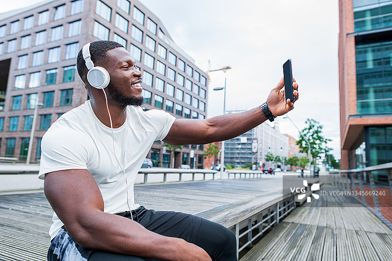 年轻的肌肉男坐在城市里听音乐图片素材
