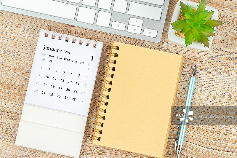 日历桌2022年1月月，顶视图日历和笔，笔记本在木桌背景。图片素材