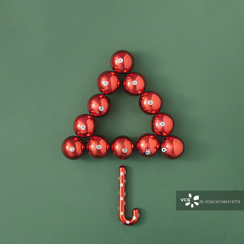 红色圣诞树装饰在绿色背景上。最小的假期概念与复制空间。新年庆祝布局。图片素材
