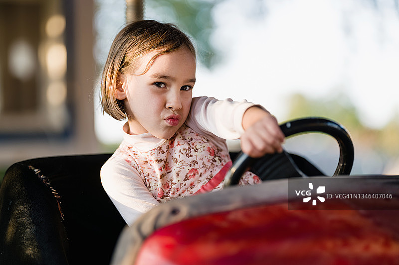 小女孩驾驶碰碰车，在户外游乐场玩图片素材