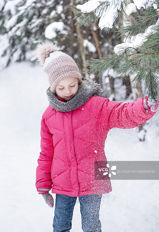 小女孩穿着鲜艳的夹克在冬天的森林里玩耍图片素材