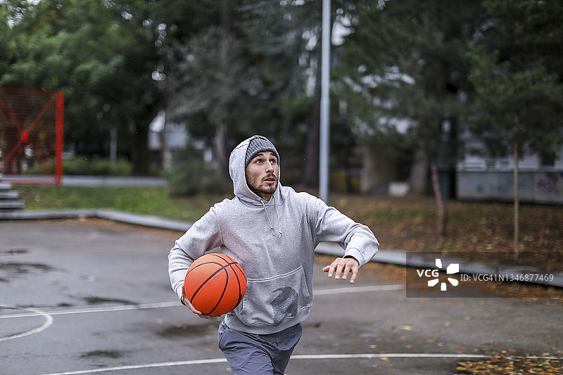 一个20多岁的年轻人在篮框上投了一个篮球图片素材