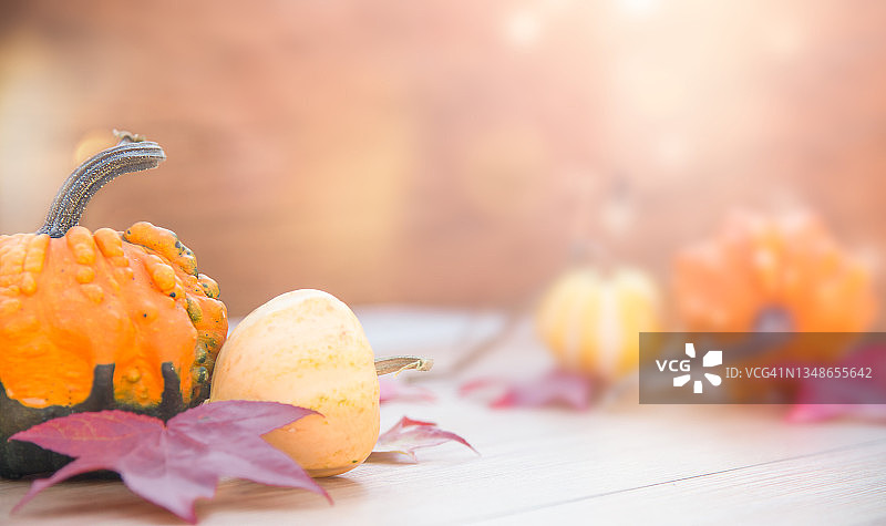 秋天装饰与南瓜和树叶在木桌上模糊的背景图片素材