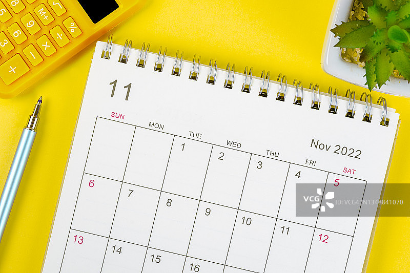 日历桌2022年11月，顶部视图日历组织者计划和笔，计算器，室内植物的黄色背景。图片素材