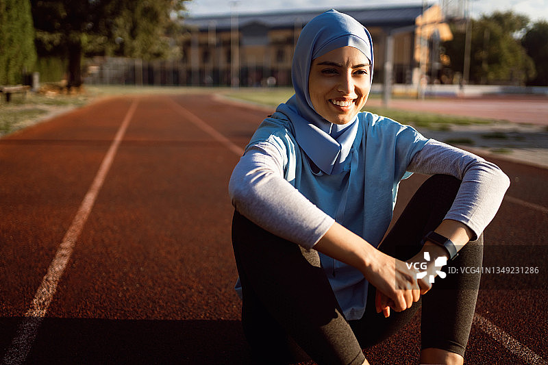 信仰伊斯兰教的敬业、开朗的女运动员，戴着头巾，穿着朴素的运动服图片素材