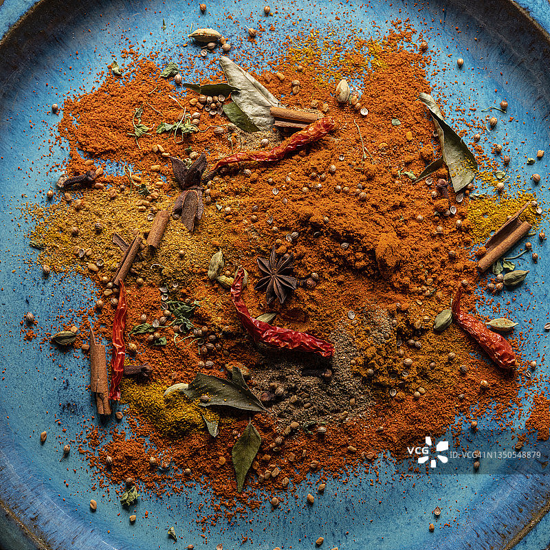 在一个古老的青绿色陶瓷盘上，有各种各样的彩色，有机，干燥，充满活力的印度食物香料。图片素材