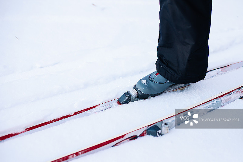 人是滑雪。特写腿在灰色的滑雪靴上滑雪，男子骑在晴朗的阳光天的雪，侧视图图片素材