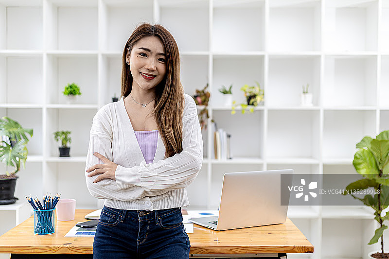 一位年轻美丽的亚洲女性站在白色办公室里的肖像，亚洲商业女性的概念形象，现代女性高管，创业女性，商业领袖女性。图片素材