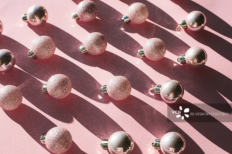 粉色发光圣诞饰品:粉红色背景上的小圆球或小装饰物图片素材