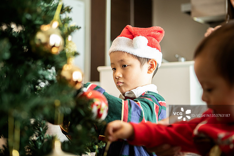 一个男孩正在认真地装饰圣诞树图片素材