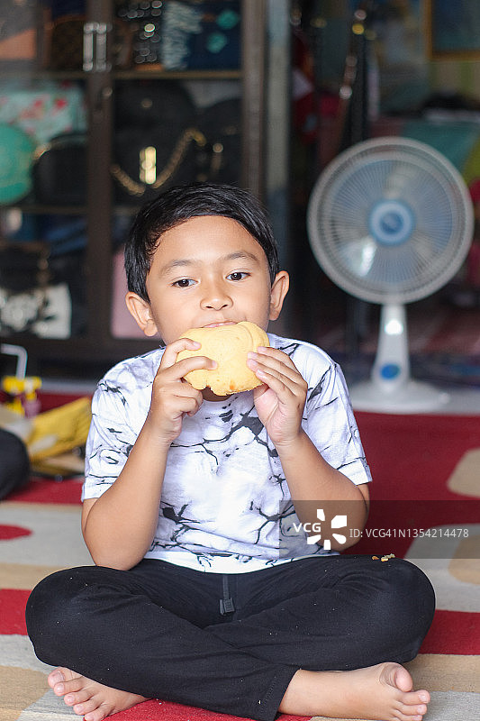 男孩坐在家里吃面包图片素材