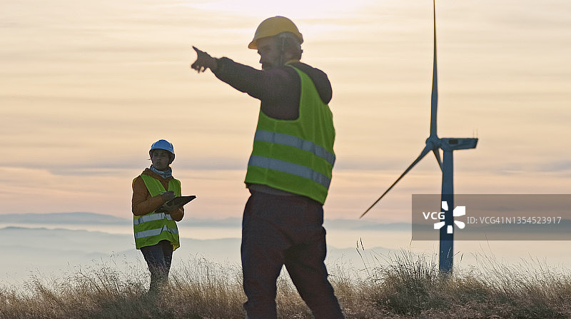 黄昏时在风电场工作的风能工程师。可再生能源系统。碳中和和可持续能源。图片素材