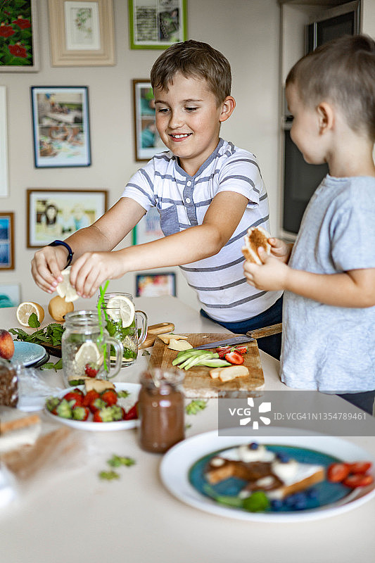 两个小弟弟用水果、浆果和巧克力酱装饰早上的三明治图片素材