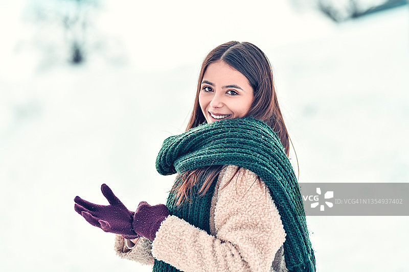 可爱的微笑女性在雪天戴上羊毛手套和厚重的披肩图片素材