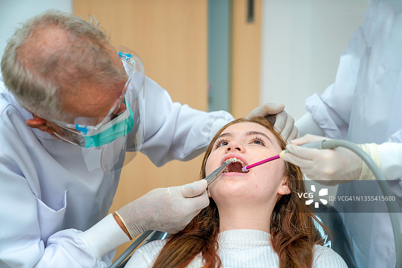 牙科医生正在手术室为女孩的牙齿进行牙科手术。图片素材