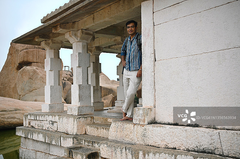 一名男子站在卡纳塔克邦汉比博尔德斯附近古老的印度教小神殿废墟中图片素材