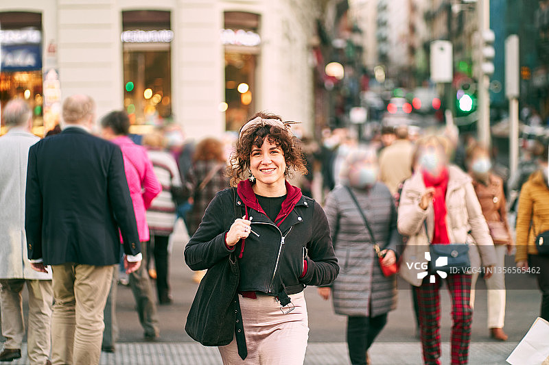 微笑的女人在人行横道上穿过拥挤的马路图片素材