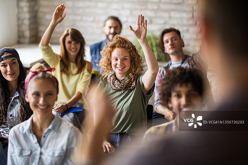 快乐的自由职业者在办公室的培训课程上举起他们的手臂。图片素材