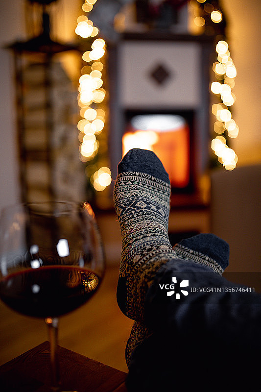 穿着羊毛袜的人在壁炉边喝着红酒图片素材