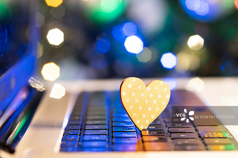 电脑键盘上的心形图案。背景是一棵装饰好的圣诞树。图片素材