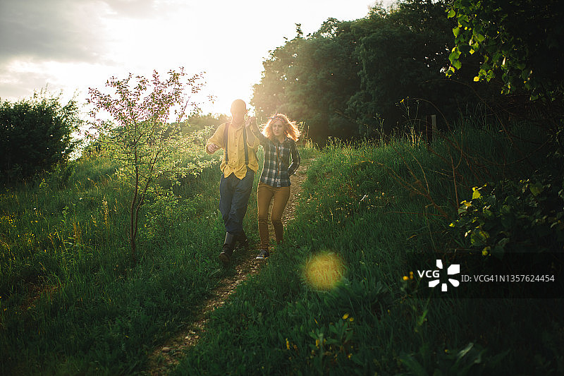 爱嬉皮士夫妇在田野里散步，亲吻，手牵着手，拥抱，躺在草地上，在夏天的日落。情人节图片素材